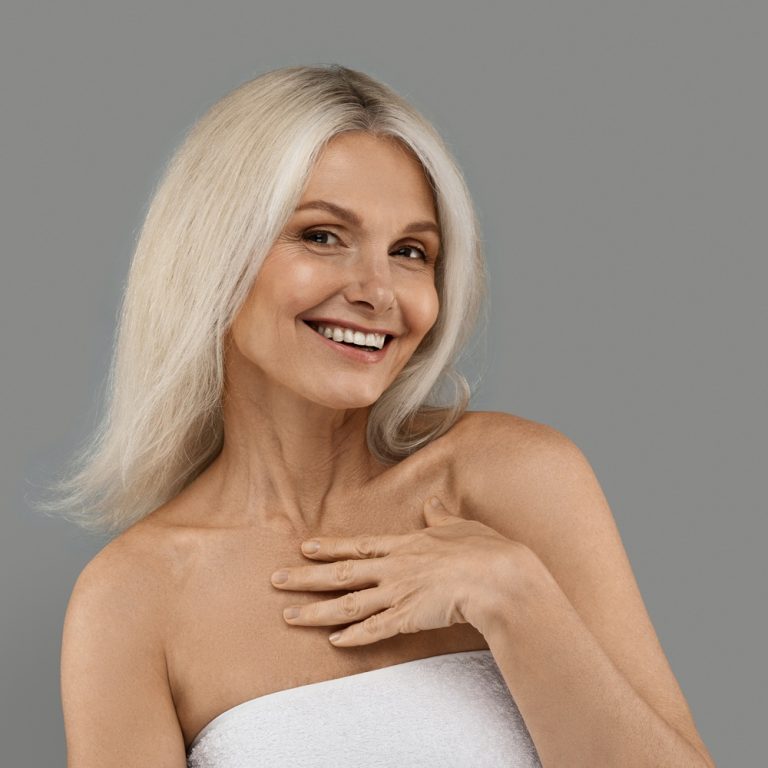 Aged Beauty. Attractive Mature Woman Wrapped in Towel Posing Over Grey Background
